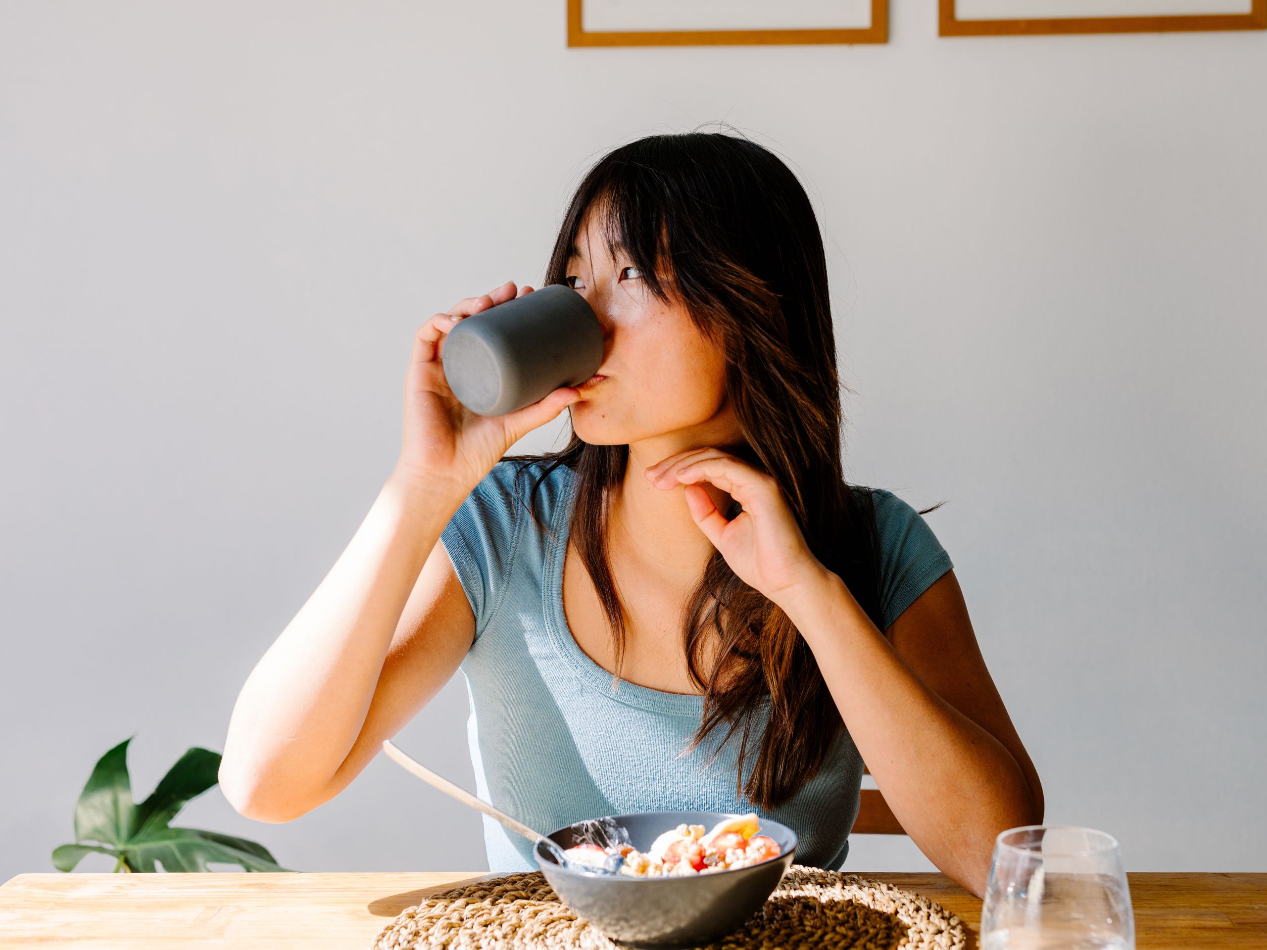 a woman sitting at a kitchen table with a bowl of yogurt in front of her
